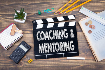 Coaching and Mentoring. movie clapper on a wooden desk.