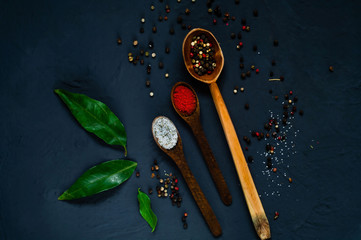 Wooden spoons and ingredients on a dark background. Concept of spicy food or cooking, top view, empty space for text