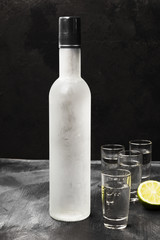 Cold vodka in shot glasses on a black background