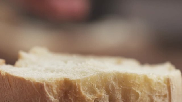 Slow motion closeup of spreading cream cheese on fresh baguette slice