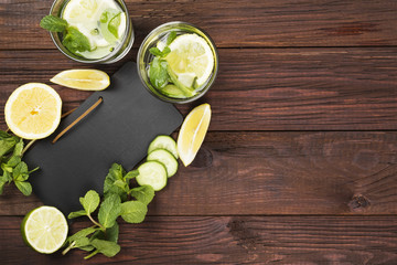 Obraz na płótnie Canvas Detox drink with cucumber, lemon and mint on a wooden background. Top view, copy space. Food background