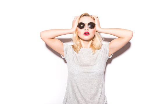 Stylish fashion sexy blonde bad crazy girl in a black t-shirt and rock sunglasses scream holding her head. Dangerous rocky emotional woman on White background