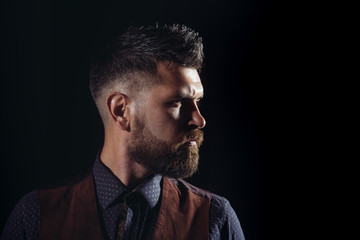 Side view portrait of confident bearded man with beautiful hairstyle. Side view portrait of thinking stylish young man. Handsome bearded young man isolated on black background.