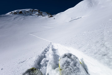 Skiers laying down switchback touring tracks to mountain pass