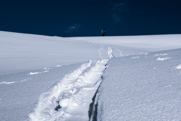 Ski touring track in powder snow with blurred skier background