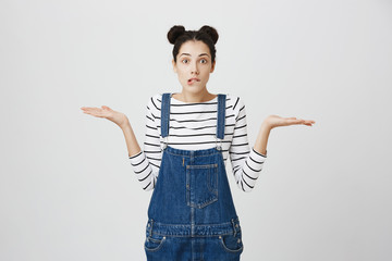 So what, Who cares. Unsure doubtful stylish brunette young woman wearing denim clothes shrugging...