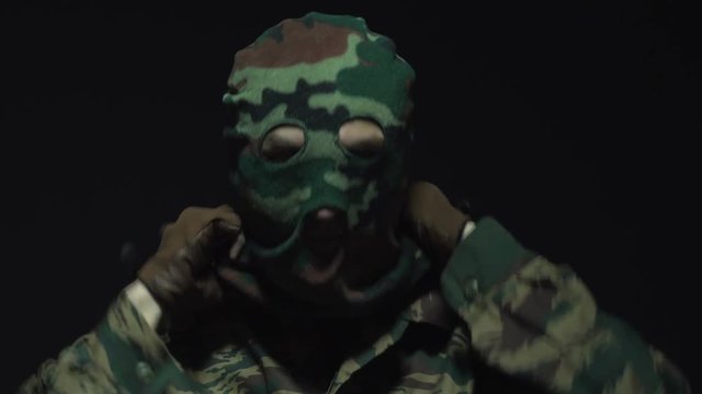 Soldier in camouflage put on his military mask