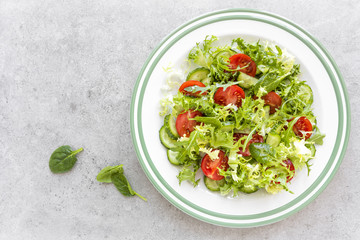 Healthy vegetable salad of fresh tomato, cucumber, spinach, frize and sesame on plate. Diet menu. Top view.