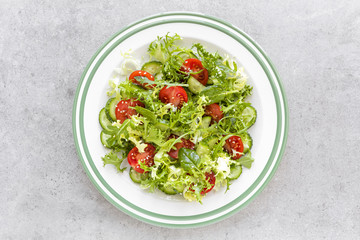 Healthy vegetable salad of fresh tomato, cucumber, spinach, frize and sesame on plate. Diet menu. Top view.