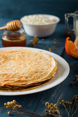 Fresh pancakes with honey, maple syrup, cottage cheese and tangerines. Wooden background. Top view