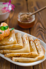 Fresh pancakes with honey, maple syrup, cottage cheese and tangerines. Wooden background. Top view