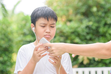 Obraz premium Young Asian boy play game on smartphone