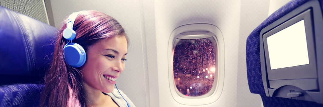 Passenger In Airplane Using Tablet Computer. Woman In Plane Cabin Using Smart Device Listening To Music On Headphones. Banner Panorama Travel People Lifestyle.