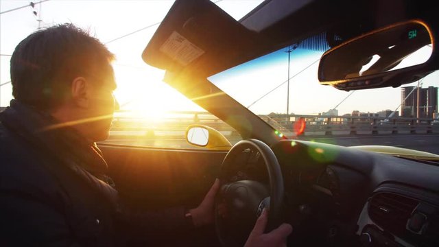Middle aged man is driving his luxurious cabriolet moving along the Golden Bridge across the Golden Horn harbour in the morning. Vladivostok, Russia