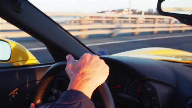 Hands on cabriolet steering wheel, road of the Golden Bridge across the Golden Horn harbour, middle aged driver's face in the mirror. Vladivostok, Russia. Morning
