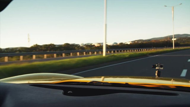 Road from moving cabriolet , view of middle aged driver's face in sunglasses in the mirror. 