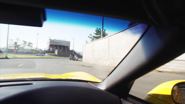 Middle-aged man in sunglasses is driving his luxurious yellow cabriolet in beautiful sunny morning. Vladivostok.
