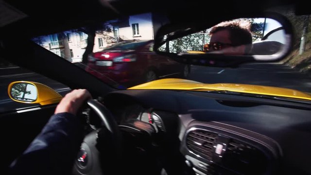 Middle-aged man in sunglasses is driving his luxurious yellow cabriolet in beautiful sunny morning. Vladivostok.