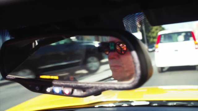Cabriolet driver's portrait in back mirror. Yellow luxurious car is driving along the Vladivostok road. Russia