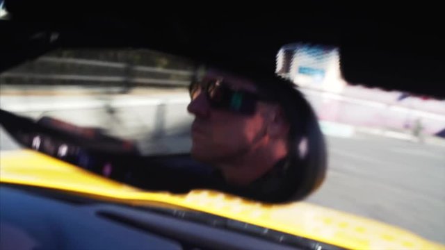 Cabriolet driver's portrait in back mirror. Yellow luxurious car is driving along the Vladivostok road. Russia