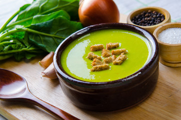Spinach soup served on wooden board 