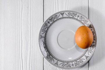 saucer with chicken egg on white boards