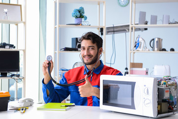 Young repairman fixing and repairing microwave oven