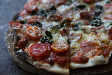 Pizza bacon ham tomato and cheese on top on wood background vintage style
