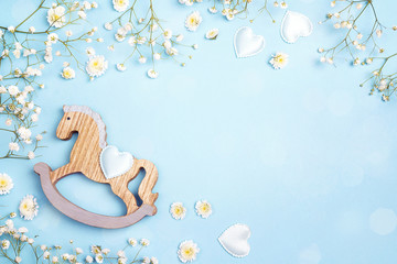 Blue background with mini rocking horse toy and gypsophila flowers. Copy space.