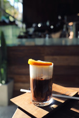 Ice black coffee with orange on wood background