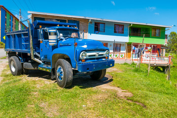 Typical Colombian blue truck and colonial houses in Guatape - Powered by Adobe