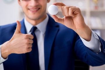Young businessman with golf ball working in office