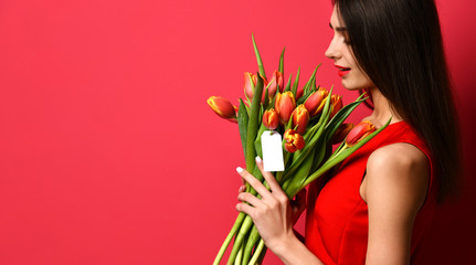 Beautiful woman with bouquet of tulip flowers in red dress and little sticker on tulips with free empty text space