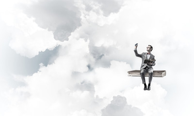 Young businessman or student floating in blue sky and studying t