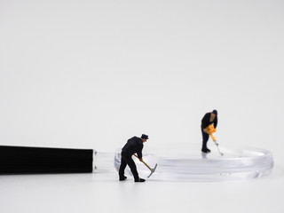 Miniature construction worker is working on a magnifying glass on a white background.