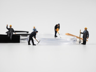 Miniature construction worker is working on a magnifying glass on a white background.