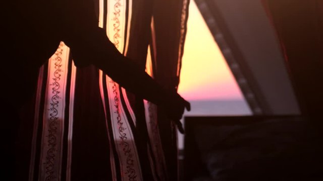 Woman hands in the morning opens curtains on big window with sea view and touches the window having a perfect cozy morning during sunrise. Slow motion. 1920x1080