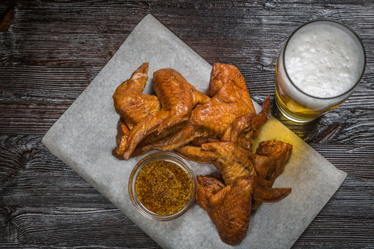 Snack to beer smoked chicken wings with a sauce of grainy mustard on the Board for filing is covered with a sheet of parchment. The view from the top. Copy-space.