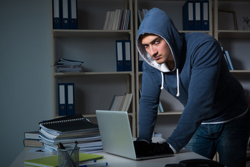 Young hacker hacking into computer at night