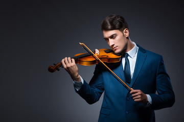 Young man playing violin in dark room