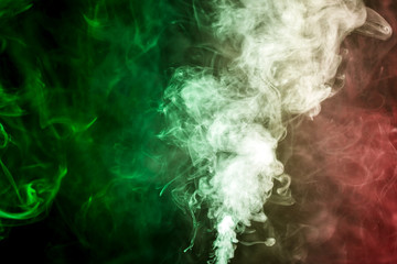Thick colorful smoke of green and red on a black isolated background. Background from the smoke of vape