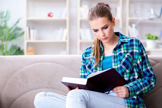 Female student reading the book  sitting on the sofa 