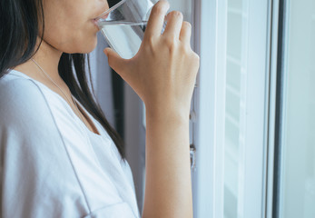 Woman drinking a glass of water after waking up