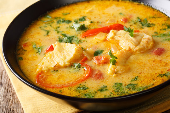 Brazilian fish Stew (Moqueca Baiana) with vegetables and coconut milk close-up on a plate. Horizontal