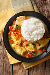 Fish stew in coconut milk with vegetables and rice close-up. Vertical top view