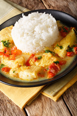 Pescado encocado or fish with coconut sauce and rice close-up on a plate. Vertical