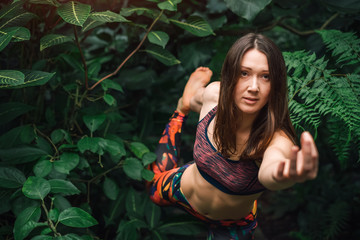 Attractive woman doing mudra and yoga balance exercise in jungle