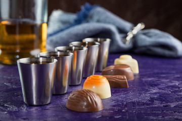 set of five servings of cognac with a variety of chocolates on a dark purple background