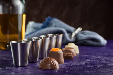 set of five servings of cognac with a variety of chocolates on a dark purple background