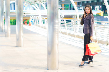 Beautiful shopper woman hand shopping with a smartphone and carrying red bag. concept of woker shopping and business online.